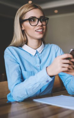 Tasarım Kursu çalışmaları için bilgi araştırma yapmak için el akıllı telefon Gadget tutan optik gözlük başarılı kadın öğrenci, kadın üniversite kampüsünde serbest zaman içinde okuyan