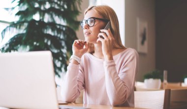 Ciddi kadın programcı dizüstü bilgisayar için sağlayıcı tedarikçisi hakkında Müşteri Hizmetleri ile tebliğ, iş arkadaşı ile önemli akıllı telefon görüşmesi yapma gözlükler konsantre kadın