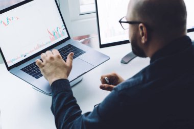 Gözlüklü bulanık kel adamın dizüstü bilgisayarı ile ofiste pencereye karşı oturması.