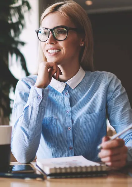 Eğitim için ders kitabı ile masada otururken üniversite projesi için fikirler hakkında olumlu öğrenci mimar düşünme, gözlüklü başarılı hipster kız kolej kampüs bakıyor