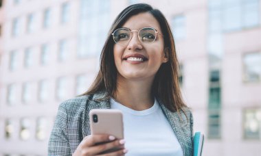 Resmi ceket giymiş, sosyal ağlardaki arkadaşlarla internet üzerinden iletişim kurarken cep telefonuyla milenyum konsepti üzerinden gülümseyen olumlu Türk bayan yöneticisi