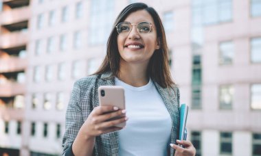 Resmi ceket giymiş, sosyal ağlardaki arkadaşlarla internet üzerinden iletişim kurarken cep telefonuyla milenyum konsepti üzerinden gülümseyen olumlu Türk bayan yöneticisi