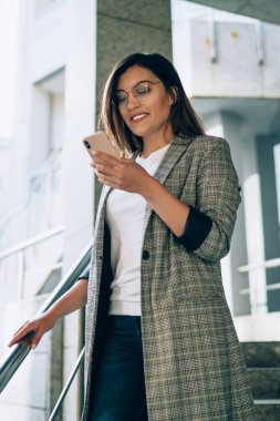 Başarılı bir kadın girişimci resmi ceket giyip internet sitesinde mesajlaşmanın keyfini sürerken akıllı telefon cihazıyla cevap veriyor. Cep telefonunda 4G kablosuz ağ kullanan genç bir kadın.