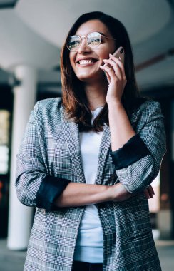 Gözlüklü gülümseyen, telefonla telefonla konuşan, cep telefonundan memnun olan, akıllı telefon konuşmalarında iyi haberler alan, mutlu hippi kız.
