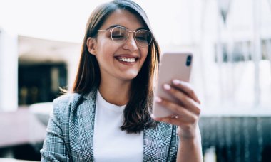 Geleceğin komedi fragmanını izlerken gülümseyen mutlu kadın film sitesi için 4G kablosuz bağlantısını kuruyor, neşeli genç blogcu takipçileriyle grup sohbetinde mesajlar alıyor