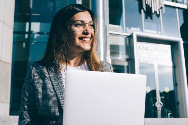 Uzaktan kumanda sırasında gülümseyen gözlüklü, vizyon düzeltme gözlüklü yetenekli kadın serbest yazar, olumlu Türk metin yazarı