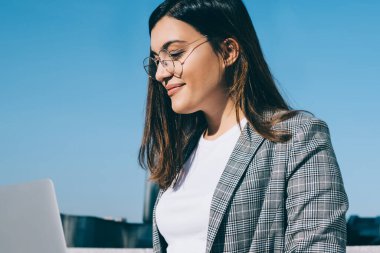 Laptop bilgisayarındaki uygulama ile posta kutusunu kontrol ederken göz falı bakılan pozitif uzaklık çalışanı, web sitesinde yayınlamak için içerik yaratan başarılı kadın