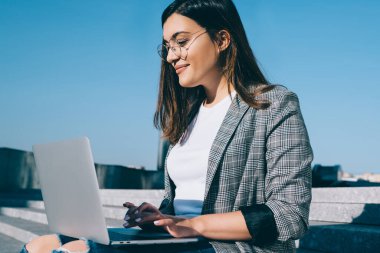 Laptop bilgisayarındaki uygulama ile posta kutusunu kontrol ederken göz falı bakılan pozitif uzaklık çalışanı, web sitesinde yayınlamak için içerik yaratan başarılı kadın