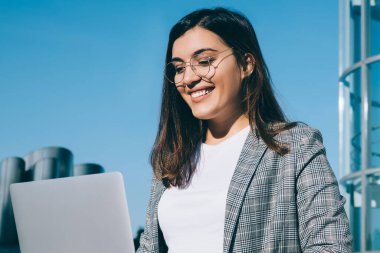 Şirin tebessümlü, klavyeli güzel bir kız öğrenci üniversitedeki derslerden sonra dinlenirken dışarıda merdivenlerde otururken dizüstü bilgisayarında çalışan neşeli mutlu bir kadın.