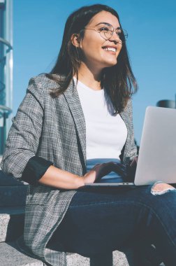 Gözlük takan neşeli Türk serbest yazar gözlerini kaçırıyor ve dizüstü bilgisayar programlarına ara verdiğinde gülüyor. Modern netbook 'lu pozitif hipster kız.