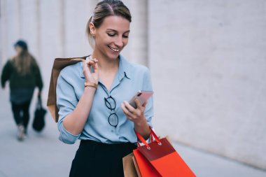 Modern uygulama üzerinden mesaj göndermek için akıllı telefon kullanan mutlu kadın, kişisel moda blogunda Kara Cuma satışları ile ilgili yayınları paketlerle paylaşan kadın müşteri