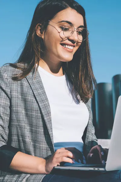 Gözlüklü mutlu genç hippi kız, internet mağazasında online alışveriş için indirimli e-postalardan kendini iyi hissederek, modern dizüstü bilgisayarla mesajları temizlemek için boş zaman harcıyor.