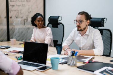 Erkek ve kadın ortaklar, bilişim projesi stratejisini tartışırken iş alanında birlikte çalışırlar. Konferans sırasında bilgiyi analiz eden çok kültürlü iş adamları.