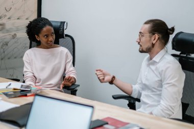 Çalışma saatleri boyunca konferans masasında birlikte çalışan çeşitli erkek ve kadın meslektaşlar, rapor oluşturma konusunda fikir alışverişinde bulunan çok kültürlü ortaklar,
