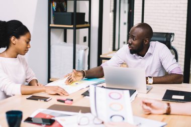 Yaratıcı erkek ve kadın tasarımcılardan oluşan çok kültürlü bir ekip beyin fırtınası sırasında ortak bir proje geliştirmek için çalışıyor, resmi olarak deneyimli iş adamları finansal raporları tartışıyorlar.