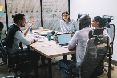 Konferans odasında beyin fırtınası sırasında şirketin finansal stratejisi konusunda işbirliği yapan zeki çok kültürlü insanlar. Masaüstü ve danışmanlık alanında birlikte oturan ciddi ortaklar.