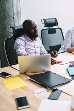 Proje üzerinde işbirliği yapmak amacıyla ofiste profesyonel iş arkadaşlarıyla birlikte otururken, akıllı telefon aygıtıyla posta yazan Kafkasyalı kadın yönetici