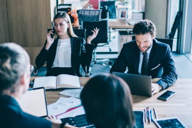 Şirket için strateji planı üzerinde çalışan iş arkadaşlarıyla birlikte masaüstünde otururken operatörden önemli bir telefon alırken internet bağlantısı kullanan ciddi bir kadın yönetmen.