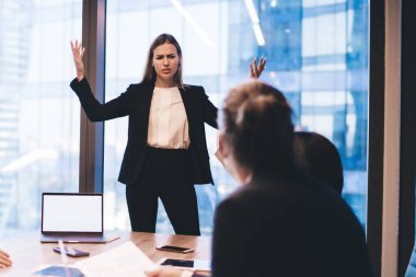 Profesyonel çalışanlarla yapılan beyin fırtınası toplantısında resmi giyinmiş kafası karışmış kadın yönetmenin şirket projesiyle ilgili sorunları var. Bir grup iş adamı bilgisayarla birlikte masaüstünde çalışıyor.