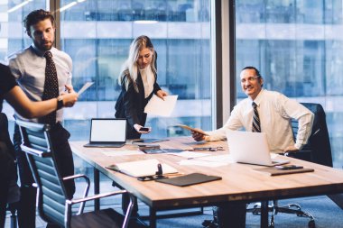 Profesyonel erkek ve kadın ortakların işbirliği süreci, masaüstü ile konferans odasında çalışırken kağıt dökümanlarından elde edilen bilgileri analiz eden zeki iş arkadaşları