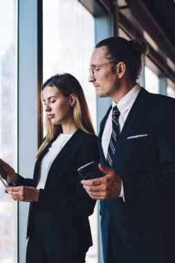 Resmi giyinmiş zeki erkek ve kadın, online iletişim için modern dijital dokunmatik pedi kullanan Kafkas iş arkadaşlarıyla birlikte finansal web sitesinden video izliyorlar.