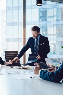 Profesyonel finans uzmanları ofis içi işbirliği sırasında rapor detaylarını tartışıyor, olgun erkek ve kadın şirket yöneticileri masaüstü yakınlarındaki bilgilerde birlikte beyin fırtınası yapıyorlar