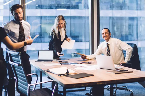 Profesyonel erkek ve kadın ortakların işbirliği süreci, masaüstü ile konferans odasında çalışırken kağıt dökümanlarından elde edilen bilgileri analiz eden zeki iş arkadaşları