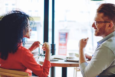 Başarılı koyu tenli girişimci arka görünüm kahve dükkanında iş toplantısı sırasında Kafkas deneyimli Yöneticisi ile birlikte konuşurken, çok kültürlü sahipleri işbirliği planı tartışmak