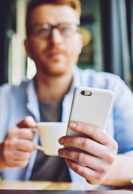 Erkek el cep telefonu tutarak ve uzakta kahve zaman kapalı sırasında uygulama güncellenmesi için beklerken bakmak seçici odak, adam modern mobil gadget 4g kablosuz internet kullanarak