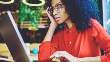 Ciddi Afro Amerikan kitap editörü uzaktan yeni bestseller okuma bölümü ile çalışma ve değişim hakkında düşünme, çekici kadın Freelancer uygulama ayarlarını öğrenmek için Webinar izliyor