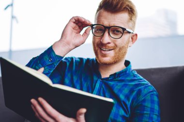 Edebiyat hobi, neşeli kafkas erkek blogger ilginç ve komik içerik arama için boş zamanlarında kameraya bakarak optik gözlük olumlu gülümseyen hipster adam Portresi