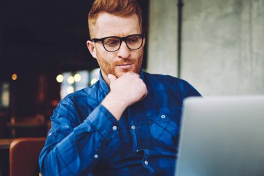 Modern netbook kapalı wifi bağlı iken online web mağazasında ödeme yapma şaşkın yetenekli hipster adam, teknoloji dünyasında yenilik hakkında haber okuma ciddi dalgın adam