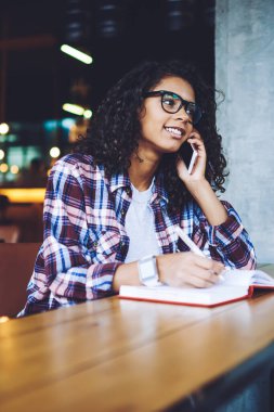 Pozitif kadın öğrenci hücresel Gadget 4g internet bağlantısı kullanarak Discus üniversite programı için arkadaşınıza arama, mutlu hipster kız kolej Kampüsü 'nde öğrenme ve mobil konuşma yapma