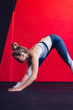 Spor salonunda antrenman yaparken esneme egzersizi yapan modaya uygun eşofman giymiş beyaz kadın sporcu, kısa tişörtlü esnek kadın ve pilates stüdyosunda ısınan taytlar.