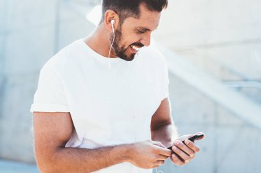 Neşeli Kafkas erkek blogcunun modern cep telefonunda kablosuz internet kullanırken içerik sitesinden komik videolar izlemesi, tişörtlü mutlu bir adamın uygulamayla haberleri okuması.