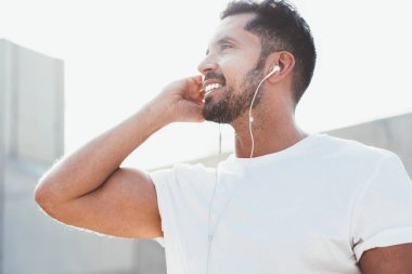 Başarılı sakallı adam elektronik kulaklıklar ve akıllı telefon uygulamaları kullanarak müziğin keyfini çıkartıyor. Şehir ortamında boş tişört konsepti ve etiket alanı için fotokopi alanı var.