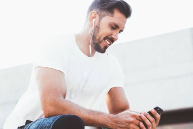 Beyaz erkek koşucu şık spor kıyafetleri giyip Wright kardiyo eğitimini yayınlıyor. Modern akıllı telefon zımbırtısıyla internete bağlı, mutlu adam sesli mesaj dinliyor.