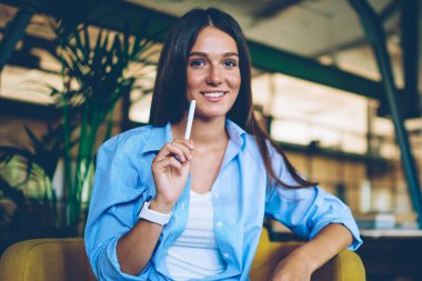 Kameraya bakan başarılı bayan öğrencinin portresi ve edebiyat camiasına makale yazma fikri. Rahat görünümlü, bilgi notlarıyla rahat koltukta oturan mutlu kadın.