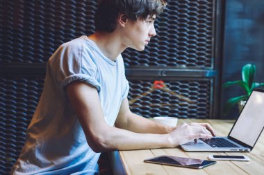 Kafkas erkek metin yazarı dizüstü bilgisayarla uzaktan çalışıyor web sitesi için yeni içerik makalesi hazırlıyor, kafeterya masasında oturan ve Netbook 'ta yazılım ve antivirüs uygulamalarını güncelliyor