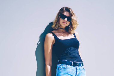 Tatillerde duvara yakın poz veren gözlüklü modaya uygun hippi kız portresi. Şehir sokaklarında yürüdükten sonra şık giyimli genç ve çekici kadın kameraya bakıyor.