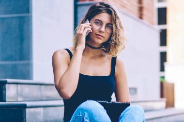 Üniversite programı hakkında danışmanlık için uluslararası telefon görüşmesi yapan çekici kız öğrencinin portresi ve klasöre not düşmesi, genç bir kadının şehir ortamında kameraya bakması