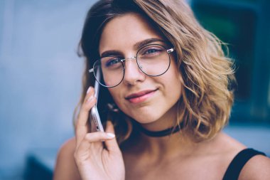 Moda güneş cep üzerinden uygulama ile olumlu dostu telefon görüşmesi yapma trendy gözlük içinde müreffeh milenyal hipster kız, cep üzerinden meslektaşım ile konuşan gülümseyen kadın portre yakın