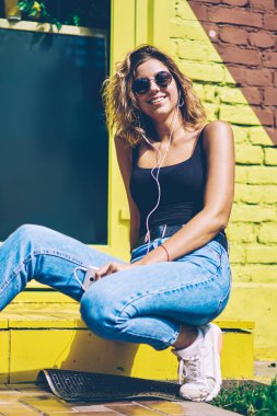 Reklam alanında güneşli yaz gününde müzik hobi için serbest zaman zevk mutlu milenyal kadın meloman portresi, neşeli hipster kız kulaklıklar ile pozitif ses çalma listesi dinleme