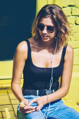 Sosyal ağdaki içerik Web sayfasında müzik haberleri okuma mutlu neşeli kadın meloman kentsel ortamda serbest zaman sırasında elektronik kulaklıklar ve mobil uygulama ile olumlu ses kayıtlarını dinlerken