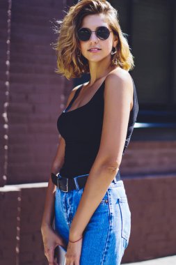 Kentsel ortamda yaz hafta sonu zevk pozitif kadın gezgin yarım uzunlukta portre, modern şehir sokaklarında serbest zaman sırasında kameraya bakarak trendy Denim giyim gülümseyen kaygısız kadın