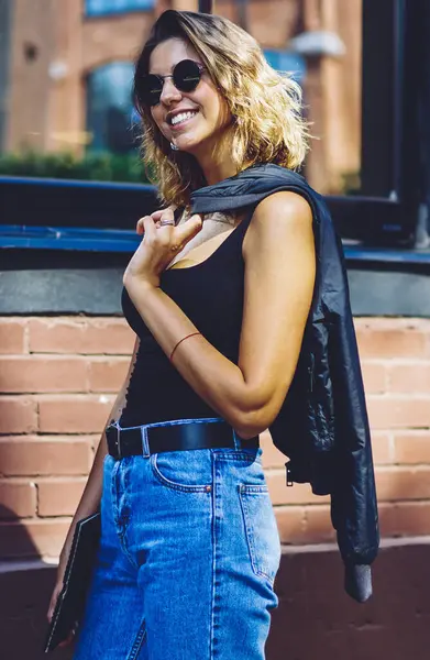 Gün zaman şehir sokakta yürüyüş diş gülümseme ile mutlu genç kadın, el klasör ve ceket ile üniversiteye dönen neşeli kadın öğrenci, sıcak hava zevk başarılı hipster kız