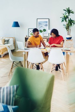 Genç Afro-Amerikalı çift masada oturmuş, birlikte planlar yapıyorlar. Koyu tenli erkek ve kadın arkadaşlar modern ev tasarımında fikirleri tartışıyorlar.