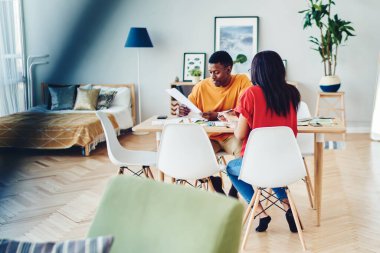 Afrika kökenli Amerikalı bir çift masada oturmuş aile bütçesinden, koyu tenli kadın ve erkeğin modern apartman dairesinde ev planları ve yaratıcı fikirleri hakkında konuşuyorlar.