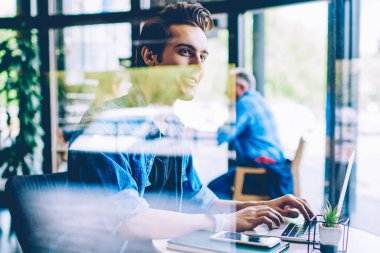 Mutlu erkek yazılım geliştiricisi uzak iş iyi duygu ve web sitesi ile program görevi tamamlandı, pozitif bin yıllık adam gülümseyen ve coworking alanında dizüstü bilgisayar cihazı kullanırken kenara bakarak