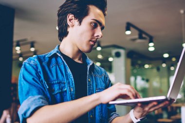 Üniversite kafeteryasında iyi wifi internet arama hotspot bağlantı seçimi Ciddi öğrenci, kendi kafeterya iç dizüstü bilgisayar ile konsantre erkek bin yıllık girişimci iş